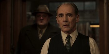Movie still from “The Outfit” (2022), directed by Graham Moore – An older man wearing a suit and a tie; Close Up shot, Over the shoulder angle