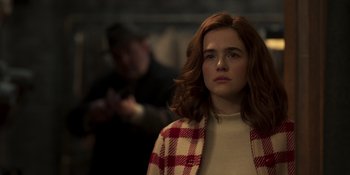 Movie still from “The Outfit” (2022), directed by Graham Moore – A woman with red hair is standing in a room; Close Up shot, Over the shoulder angle