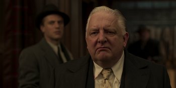Movie still from “The Outfit” (2022), directed by Graham Moore – An older man wearing a suit and tie; Close Up shot, Low angle