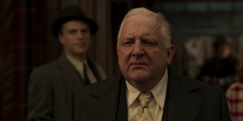 Movie still from “The Outfit” (2022), directed by Graham Moore – An older man wearing a suit and tie; Close Up shot, Low angle