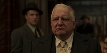 Movie still from “The Outfit” (2022), directed by Graham Moore – An older man in a suit and tie; Close Up shot, Low angle