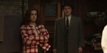 Movie still from “The Outfit” (2022), directed by Graham Moore – A man and a woman standing next to each other; Medium shot, Low angle