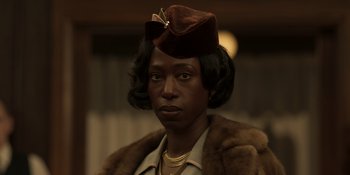 Movie still from “The Outfit” (2022), directed by Graham Moore – A woman wearing a brown hat and a brown coat; Close Up shot, Over the shoulder angle