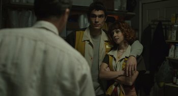 Movie still from “The Passenger” (2023), directed by Carter Smith – A man and a woman standing next to each other in a room; Medium shot, Over the shoulder angle