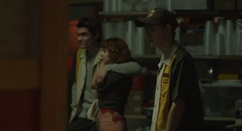 Movie still from “The Passenger” (2023), directed by Carter Smith – A group of people standing in a room; Medium shot, Over the shoulder angle