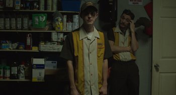 Movie still from “The Passenger” (2023), directed by Carter Smith – A man standing next to another man in a store; Medium shot, Low angle
