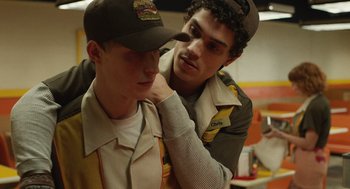 Movie still from “The Passenger” (2023), directed by Carter Smith – A man putting a cap on another man's head; Close Up shot, Over the shoulder angle