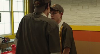 Movie still from “The Passenger” (2023), directed by Carter Smith – Two young men standing next to each other in front of a brick wall; Medium shot, Over the shoulder angle