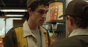 Movie still from “The Passenger” (2023), directed by Carter Smith – A young man in a hat and jacket talking to another man; Close Up shot, Over the shoulder angle