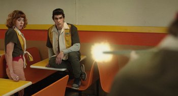 Movie still from “The Passenger” (2023), directed by Carter Smith – A man sitting on a bench in a room; Medium shot, Low angle