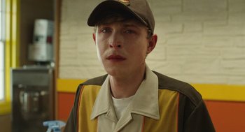 Movie still from “The Passenger” (2023), directed by Carter Smith – A young man wearing a baseball cap and jacket; Close Up shot, Over the shoulder angle