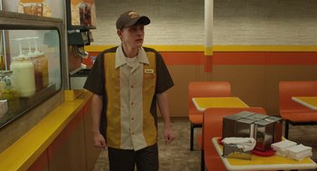 Movie still from “The Passenger” (2023), directed by Carter Smith – A man standing in front of a table in a restaurant; Medium shot, Over the shoulder angle