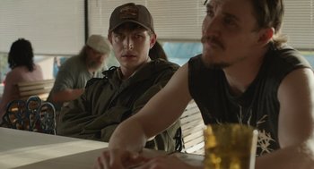 Movie still from “The Passenger” (2023), directed by Carter Smith – Two men sitting at a table in front of each other; Close Up shot, Over the shoulder angle