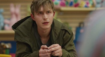 Movie still from “The Passenger” (2023), directed by Carter Smith – A man in a green jacket is holding his hands together; Close Up shot, Over the shoulder angle