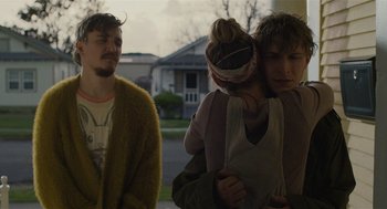 Movie still from “The Passenger” (2023), directed by Carter Smith – A group of people standing next to each other on the street; Medium shot, Over the shoulder angle