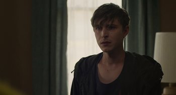Movie still from “The Passenger” (2023), directed by Carter Smith – A young man standing in front of a window; Close Up shot, Over the shoulder angle