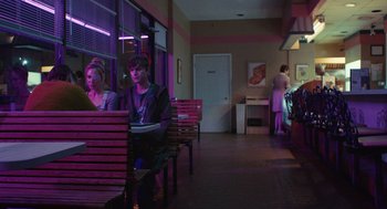 Movie still from “The Passenger” (2023), directed by Carter Smith – A man and woman sitting at a table in front of a window; Wide shot, Over the shoulder angle