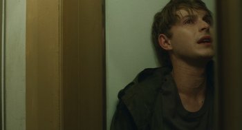 Movie still from “The Passenger” (2023), directed by Carter Smith – A man leaning up against a wall with his eyes closed; Close Up shot, Over the shoulder angle