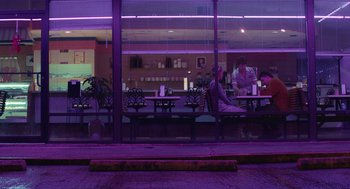 Movie still from “The Passenger” (2023), directed by Carter Smith – Two people sitting at a table in front of a window; Wide shot, Over the shoulder angle