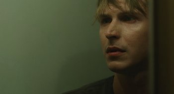 Movie still from “The Passenger” (2023), directed by Carter Smith – A man's face in front of a green wall; Close Up shot, High angle