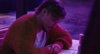 Movie still from “The Passenger” (2023), directed by Carter Smith – A man sitting at a table with his eyes closed; Medium shot, High angle