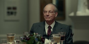 Movie still from “Dopesick” (2021), directed by Danny Strong – An older man sitting at a table with a glass of wine; Close Up shot, Over the shoulder angle