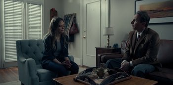 Movie still from “Dopesick” (2021), directed by Danny Strong – Two people sitting in a living room talking to each other; Medium shot, Over the shoulder angle