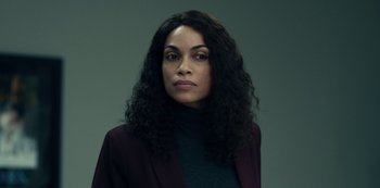 Movie still from “Dopesick” (2021), directed by Danny Strong – A woman with long black curly hair wearing a purple jacket; Close Up shot, Low angle