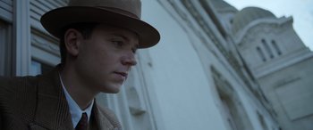 Movie still from “The Pigeon Tunnel” (2023), directed by Errol Morris – A man wearing a brown hat and a coat; Close Up shot, Low angle