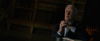 Movie still from “The Pigeon Tunnel” (2023), directed by Errol Morris – An older man sitting in front of a book shelf; Close Up shot, Over the shoulder angle