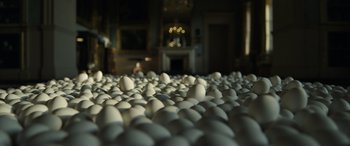 Movie still from “The Pigeon Tunnel” (2023), directed by Errol Morris – A room filled with lots of white eggs on the floor; Wide shot, Low angle