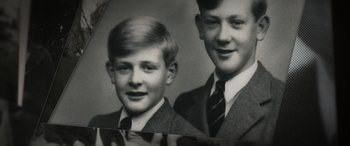 Movie still from “The Pigeon Tunnel” (2023), directed by Errol Morris – Two young men in suits are posing for a picture; Extreme Close Up shot, Overhead angle
