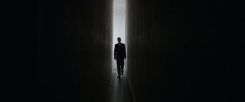 Movie still from “The Pigeon Tunnel” (2023), directed by Errol Morris – A man in a suit is standing in a tunnel; Wide shot, Low angle