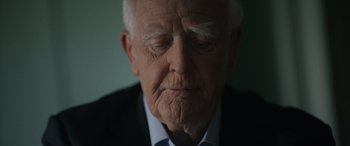 Movie still from “The Pigeon Tunnel” (2023), directed by Errol Morris – An older man in a suit and tie; Close Up shot, Over the shoulder angle