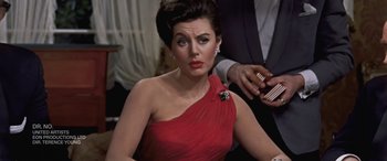 Movie still from “The Pigeon Tunnel” (2023), directed by Errol Morris – A woman in a red dress holding a cell phone; Close Up shot, Over the shoulder angle
