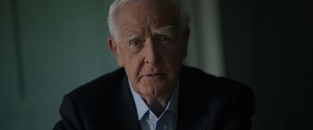 Movie still from “The Pigeon Tunnel” (2023), directed by Errol Morris – An older man wearing a suit and a white shirt; Close Up shot, Low angle