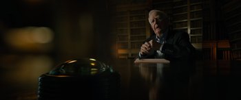 Movie still from “The Pigeon Tunnel” (2023), directed by Errol Morris – An older man sitting at a table in a library; Medium shot, Low angle