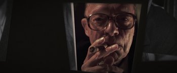 Movie still from “The Pigeon Tunnel” (2023), directed by Errol Morris – An older man with glasses smoking a cigarette in front of a mirror; Close Up shot, Low angle