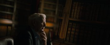 Movie still from “The Pigeon Tunnel” (2023), directed by Errol Morris – An older man sitting in front of a book shelf; Close Up shot, Over the shoulder angle