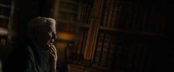 Movie still from “The Pigeon Tunnel” (2023), directed by Errol Morris – An older man sitting in front of a book shelf; Close Up shot, Over the shoulder angle