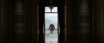 Movie still from “The Pigeon Tunnel” (2023), directed by Errol Morris – An older man sitting on a balcony looking out a window; Wide shot, Low angle