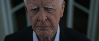 Movie still from “The Pigeon Tunnel” (2023), directed by Errol Morris – An old man with a frowning look on his face; Close Up shot, Over the shoulder angle