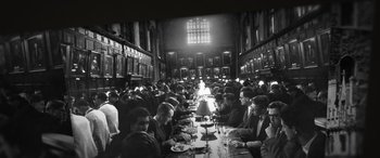 Movie still from “The Pigeon Tunnel” (2023), directed by Errol Morris – A group of people sitting at a long dining table; Wide shot, High angle