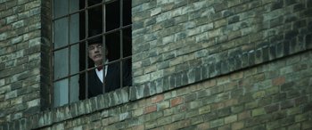 Movie still from “The Pigeon Tunnel” (2023), directed by Errol Morris – A man in a suit and red tie looking out of a window; Medium shot, Low angle