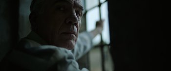 Movie still from “The Pigeon Tunnel” (2023), directed by Errol Morris – An older man looking out of a jail cell window; Close Up shot, Low angle