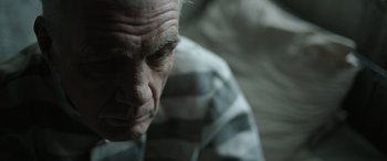 Movie still from “The Pigeon Tunnel” (2023), directed by Errol Morris – An older man in a striped shirt looking down; Close Up shot, High angle