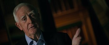 Movie still from “The Pigeon Tunnel” (2023), directed by Errol Morris – An older man wearing a suit and tie; Close Up shot, Over the shoulder angle