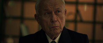 Movie still from “The Pigeon Tunnel” (2023), directed by Errol Morris – An older man in a suit and tie looking at the camera; Close Up shot, Low angle