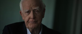 Movie still from “The Pigeon Tunnel” (2023), directed by Errol Morris – An old man in a black suit and white shirt; Close Up shot, Over the shoulder angle