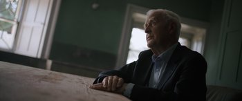 Movie still from “The Pigeon Tunnel” (2023), directed by Errol Morris – An older man sitting at a table looking up; Close Up shot, Low angle